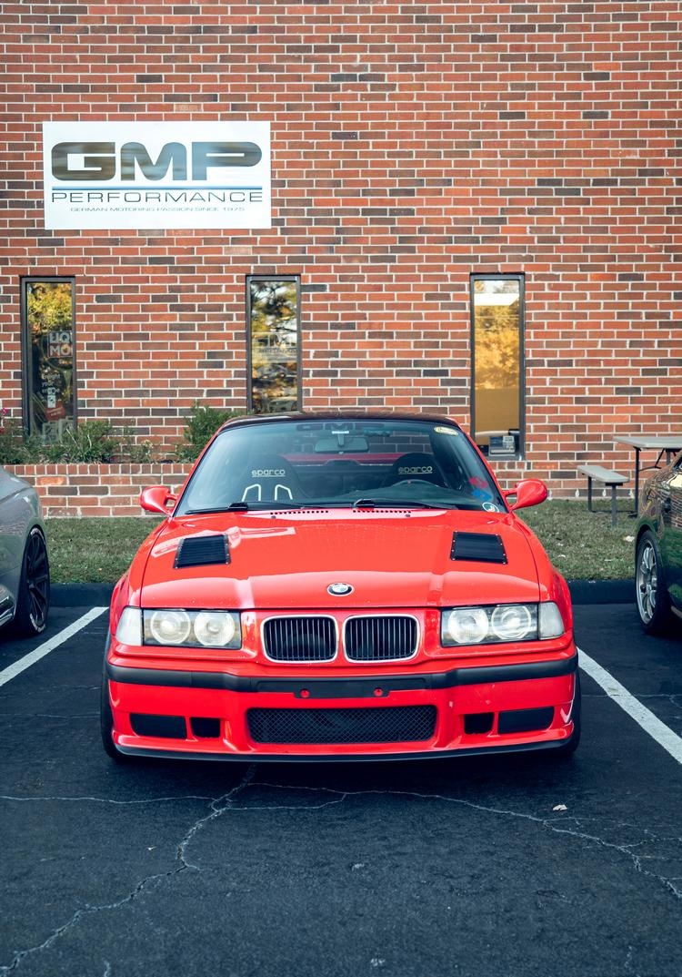 A red E36 BMW parked under the GMP Performance sign